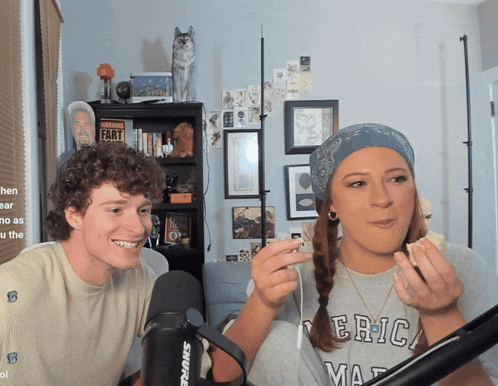 a man and a woman are sitting in front of a shure microphone in a room