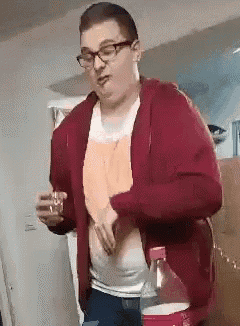 a man wearing glasses and a red hoodie is holding a glass of water .