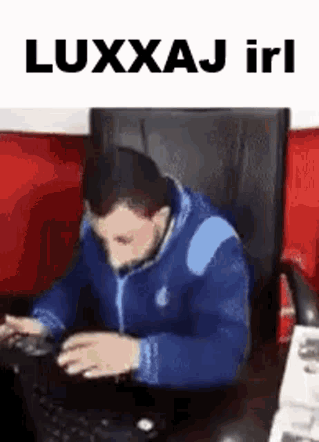 a man in a blue jacket is sitting in a chair using a laptop computer .