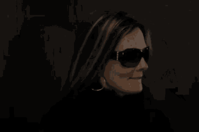 a woman is adjusting her sunglasses in the dark .