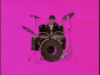 a person is playing drums on a pink background .
