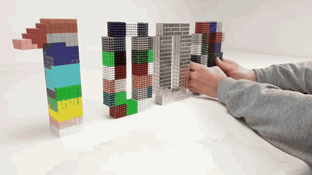 a person is playing with a stack of magnets that looks like lego blocks