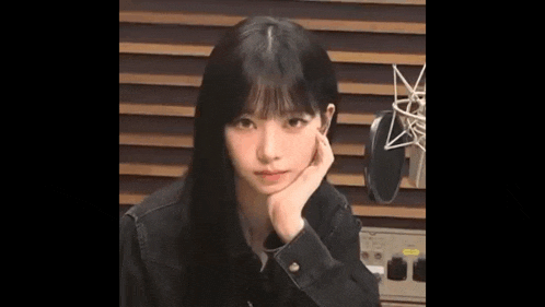 a young woman is sitting in front of a microphone with her hand on her face .