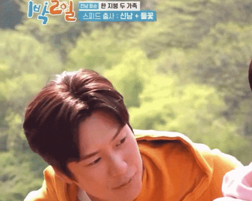 a man in a yellow sweatshirt is looking down with a foreign language written on the bottom