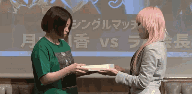 a woman in a green shirt is giving another woman a book