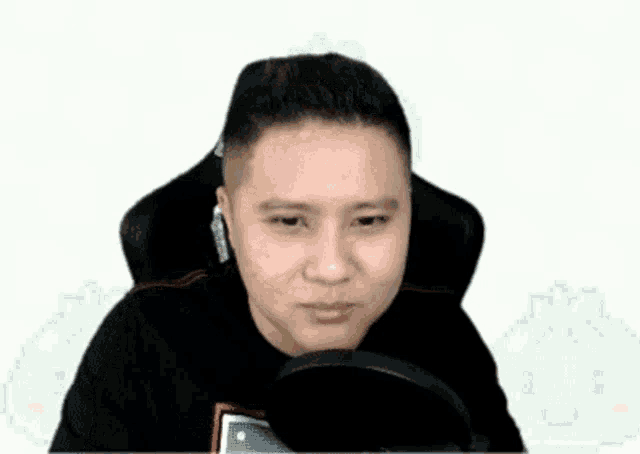 a man is sitting in a chair with a microphone in front of him and making a funny face .