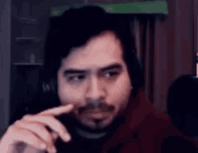 a man with a beard is wearing headphones and making a funny face while looking at the camera .