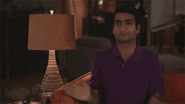 a man in a purple shirt is sitting on a couch and saying let 's get to work