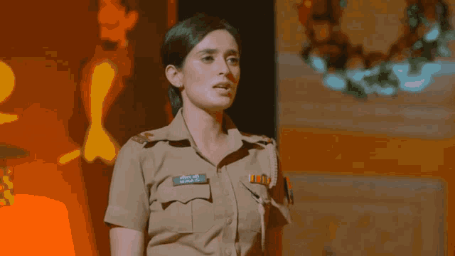 a woman in a police uniform is standing with her arms outstretched in front of a wreath .