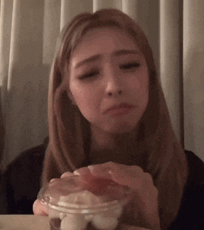 a woman is sitting at a table with a cup of food in her hands .