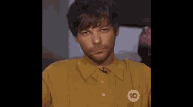 a close up of a man wearing a yellow shirt with a logo on it .