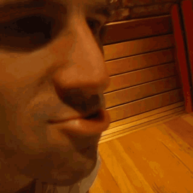a close up of a man 's face with a wooden wall behind him