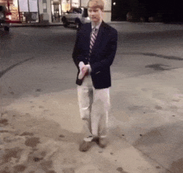 a man in a suit and tie is walking down the sidewalk