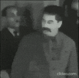 a black and white photo of a man with a mustache standing in front of a group of men .