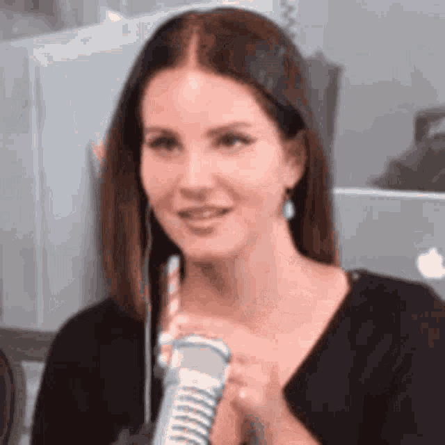 a woman is smiling while holding a microphone in her hand .