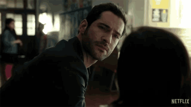 a man with a beard is looking at a woman with a netflix logo in the corner