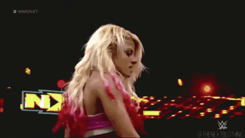 a blonde woman is standing in front of a sign that says nxt .