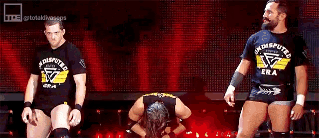 a group of wrestlers are standing on a stage with one wearing a shirt that says ' undisputed era '
