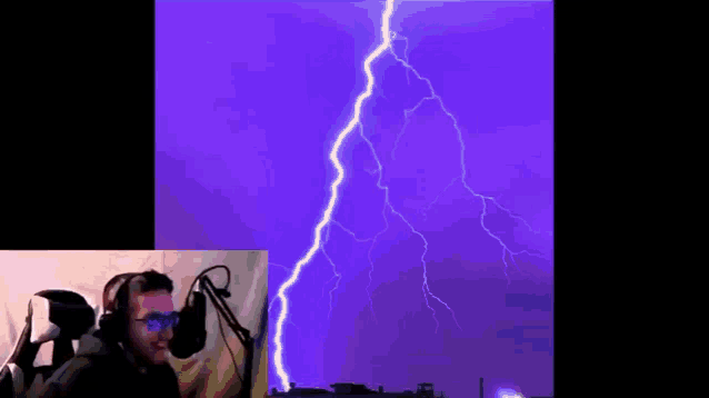 a man wearing headphones is watching a lightning strike