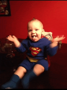 a baby dressed in a superman costume is sitting on a table