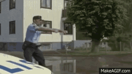 a police officer is standing on the back of a police car and pointing .