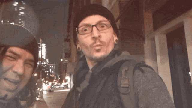 two men are posing for a picture and one has a backpack