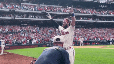 a man wearing a phillies jersey stands on the field