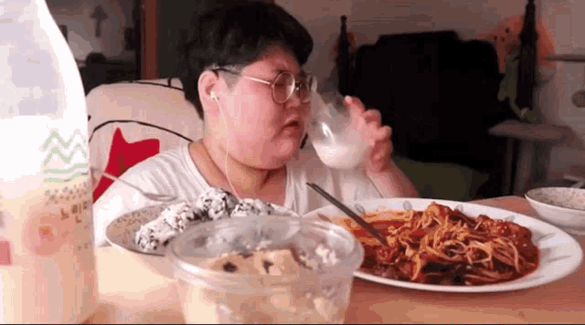 a person is sitting at a table with a plate of food and a glass of milk