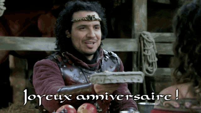 a man with a crown on his head is holding a piece of cake with the words joyeux anniversaire below him