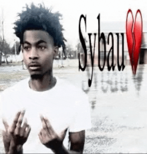 a young man in a white shirt is giving the middle finger while standing in front of a broken heart .