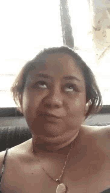 a woman is wearing a necklace and making a funny face while sitting on a couch .