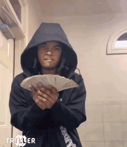 a person in a hoodie holding a bunch of money