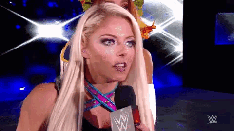 a female wrestler speaking into a microphone with a wwe logo behind her