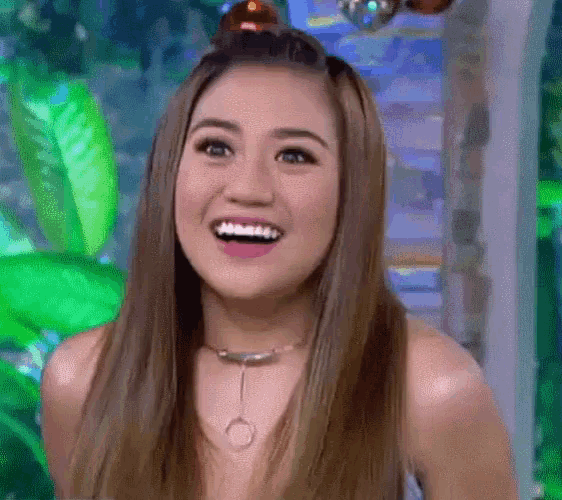 a woman with long hair and a choker is smiling .