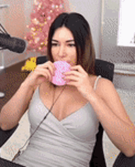 a woman is sitting in front of a microphone eating a donut .
