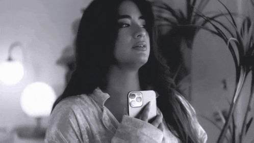 a black and white photo of a woman holding her phone
