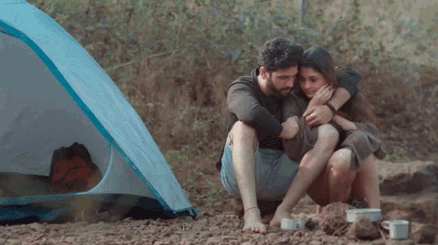 a man and a woman sitting in front of a tent