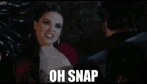 a man with a beard is standing next to a woman in a dark room and saying oh snap .