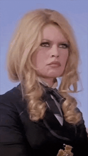 a woman with blonde hair is wearing a black jacket and a tie