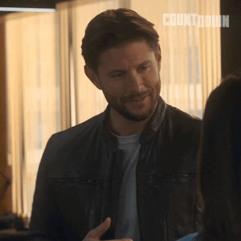 a man in a leather jacket is smiling while talking to a woman