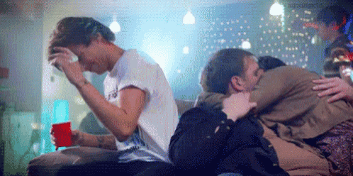 a group of people are sitting on a couch hugging each other and one of them is crying .