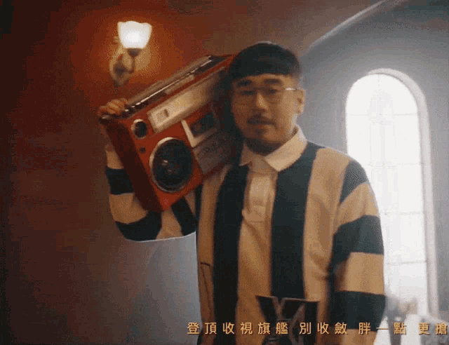 a man in a striped shirt is holding a boombox over his shoulder