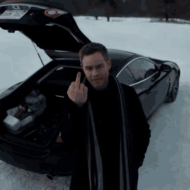 a man is giving the middle finger in front of a car with a license plate that says bnn 76c