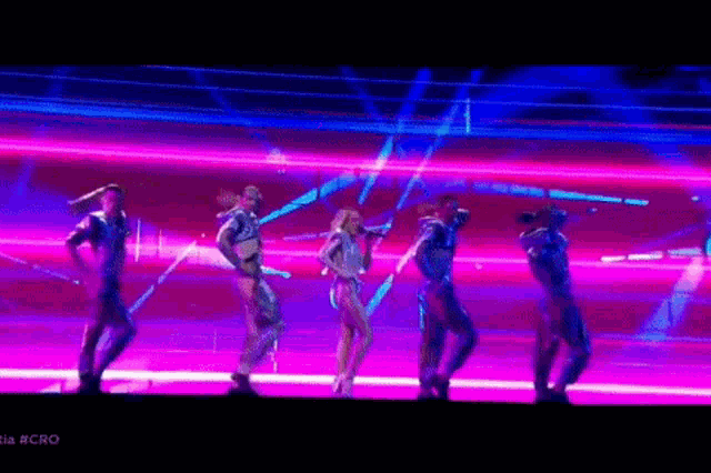 a group of people are dancing and singing on a stage with the word cro on the bottom right