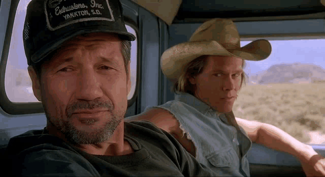 two men wearing cowboy hats are sitting in a truck