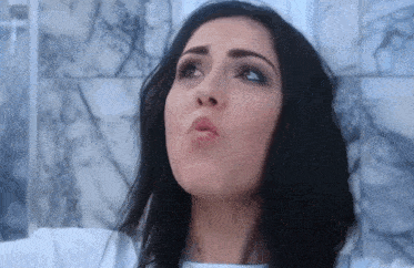a woman with dark hair is making a funny face with her mouth open