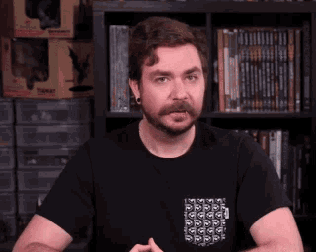a man wearing a black t-shirt with a pocket that has a pattern on it