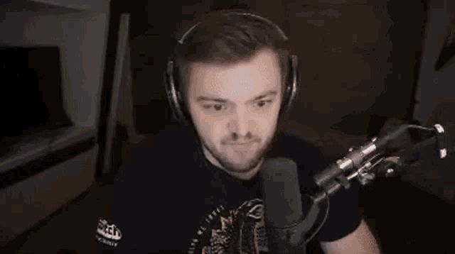 a man wearing headphones is sitting in front of a microphone in a room .