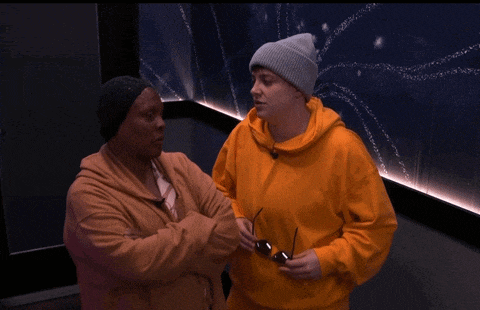 a man wearing a beanie and a woman wearing a sweater are standing next to each other