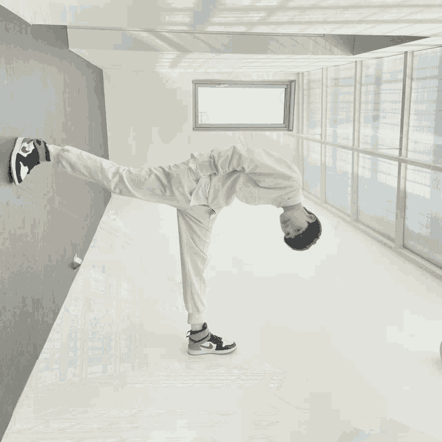 a man wearing a white sweatshirt and black and red nike shoes is standing in a hallway